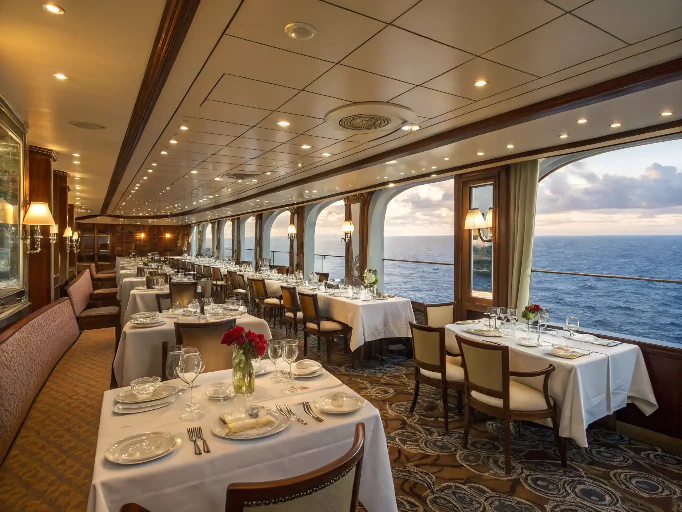 A beautifully set table in a cruise ship dining room, featuring gourmet dishes, fine wines, and attentive waitstaff, showcasing the luxurious dining experience offered on Mass Excursions cruises.